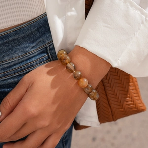 Close-up of amber patterned acrylic beaded bracelet worn by a model in a trendy outfit