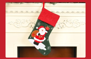 Detail of dark green linen Christmas stocking with Santa Claus embroidery on a fireplace