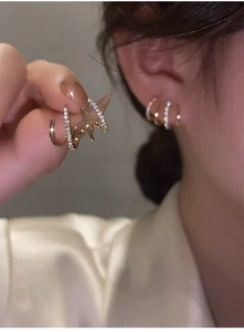 Close-up of gold-plated four-claw stud earrings with cubic zirconia on silk background