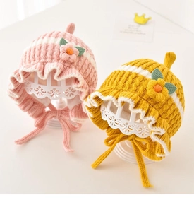 Detailed knit texture of baby hats with floral accents and scalloped ruffle edges