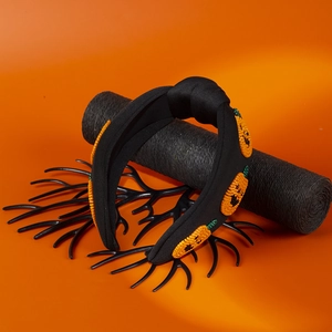 Detail of knotted black fabric headband with handmade beaded orange pumpkin patches