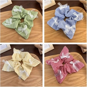 Collage of four checkered fabric scrunchies with lace bows on a rustic wooden tray
