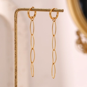 Macro detail of 18K gold-plated long oval link drop earrings on a minimalist display stand