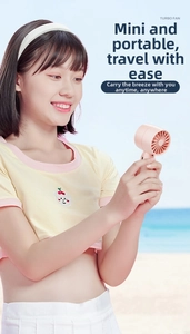 Pink handheld mini turbo fan shown being used by a model at the beach for summer cooling
