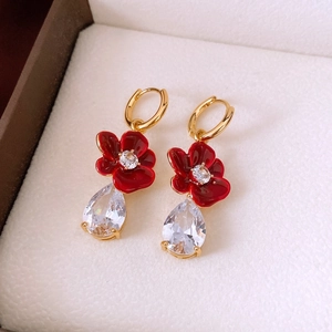 Detailed macro view of 18k gold vintage flower earrings with zircon and red enamel