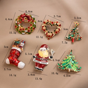 Detailed view of Christmas brooches with specific size and weight data on a beige fabric