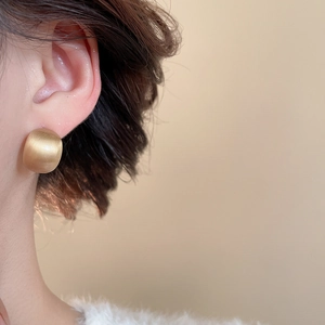 Macro detail of vintage gold floral stud earring with brushed metal texture and matte finish