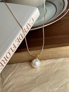 Close-up of a white pearl pendant on a thin gold chain over a French vintage book