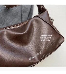 Top detail view of dark brown litchi textured leather underarm bag with zipper and logo