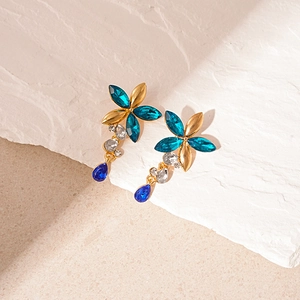 Close-up of vintage flower earrings with blue teardrop crystals and gold-tone finish