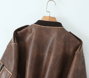Détail d'un blouson vintage en similicuir marron avec col côtelé et pattes d'épaule