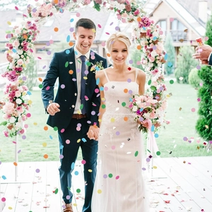 Outdoor wedding scene featuring colorful round paper confetti falling over the happy couple