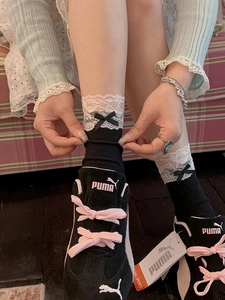 Détail de chaussettes mi-mollet en coton noir avec dentelle blanche et nœuds satin