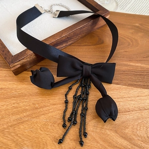Detail of elegant black satin bow necklace featuring delicate beaded fringe and silver clasp