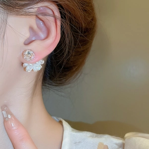 Detailaufnahme eines geschichteten weißen Blumenohrrings mit Zirkonia auf einem weiblichen Model
