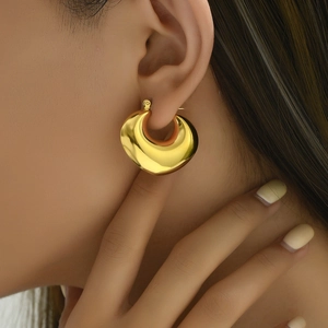 Gros plan de boucles d'oreilles créoles dorées épaisses avec finition poli miroir