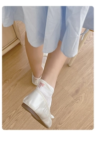 Close-up of pink bow embroidery on white mesh socks with elegant satin flat shoes
