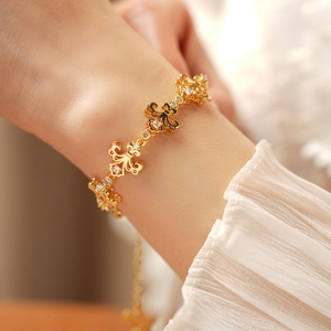 Gros plan d'un bracelet fleur de lys doré avec cristaux porté sur le poignet