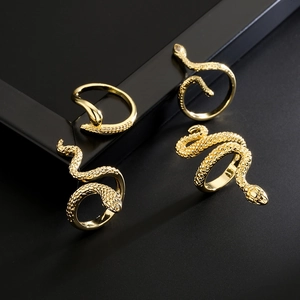 Set of 18K gold plated snake and geometric rings with zircon accents on black background