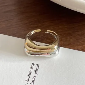 Makroaufnahme von minimalistischem silbernem und goldenem Ring im Wellen-Design