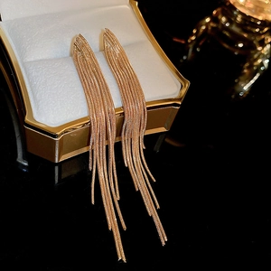 Elegant gold V-shaped long fringe drop earrings hanging on a luxury jewelry box