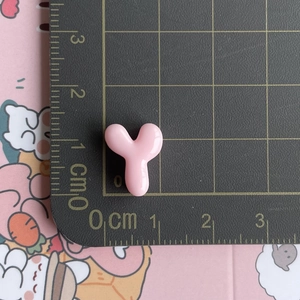 Macro shot of pink resin letter Y accessory with dimension measurements on cutting mat