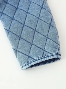 Close-up of diamond quilted pattern and washed denim texture on the jacket sleeve cuff