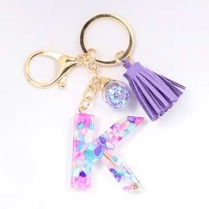 Detail of letter K crystal resin keychain with purple tassels and crushed stone infill