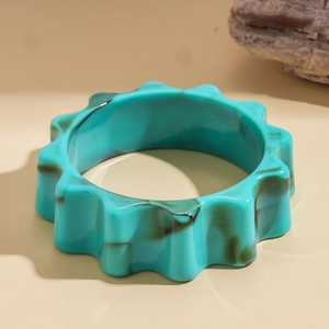 Dettaglio del bracciale in acrilico marmorizzato verde acqua con bordi a onde