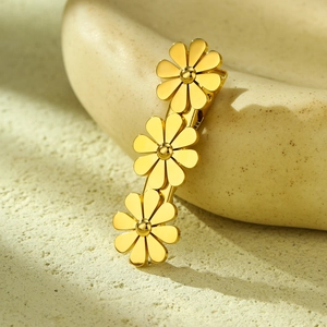 Elegant gold metal hair clip featuring three vertical daisy flowers on ceramic background