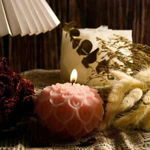 Close-up of a lit lotus shaped pink scented candle on a vintage decorative background