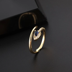 Macro shot of gold snake-shaped ring with a pear-cut blue stone and zircon halo