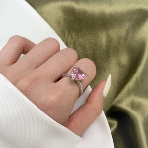 Close-up of heart-shaped pink zircon ring with micro-pave setting on a silver band