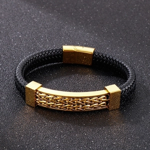 Macro view of men's black leather braided bracelet with gold textured metal plaque and clasp