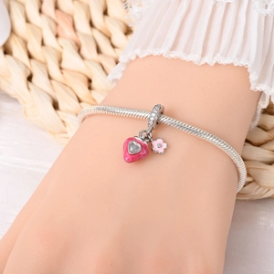 Detailansicht eines silbernen Schlangenarmbands mit rosa Erdbeer- und Blumenanhängern