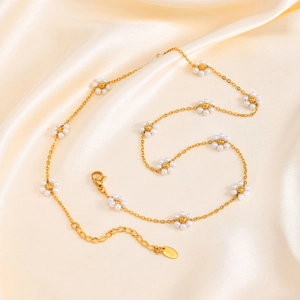 Detail of gold daisy necklace with white pearls on a silk fabric background