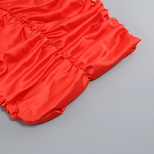 Detail aus rotem Satinstoff mit eleganter Raffung und hochwertiger, glänzender Textur