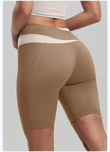 Detail of high-waist yoga shorts featuring color-block design and peach lift stitching