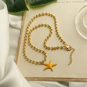 Detail of gold beaded necklace with orange starfish pendant on vintage background