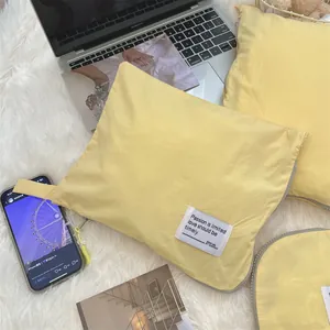 Waterproof yellow travel storage bags set on plush rug near laptop and smartphone