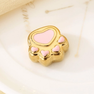 Macro shot of a golden stainless steel cat paw pendant with pink enamel heart detail