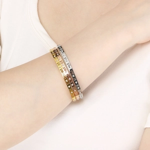 Close-up of three-color roman numeral bangles with sparkling crystals on model's wrist