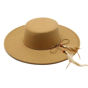 Detailed view of camel wool flat top hat with beads and feather trim decoration