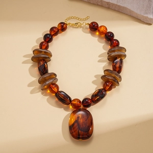 Detail view of amber resin beads and marble-textured discs on a golden chain necklace