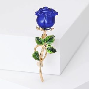 Detailed view of blue enamel rose brooch with golden stem and green leaf accents