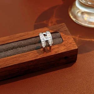 Nahaufnahme des H-förmigen Silberrings mit Baguette-Zirkonia auf dunklem Holzdisplay