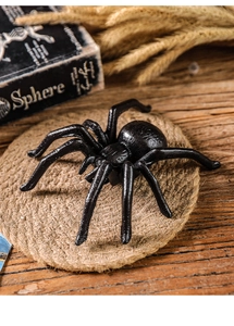 Detailed realistic black spider figurine model displayed on a rustic woven mat