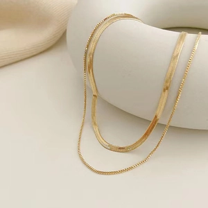 Collana a doppio strato dorata a serpente e a scatola su un espositore circolare bianco
