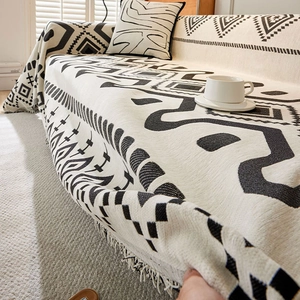 Detail of bohemian chenille sofa cover showing black and white geometric pattern and fringe