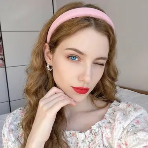 Detailed close-up of a pink wide headband and silver earrings worn by a model